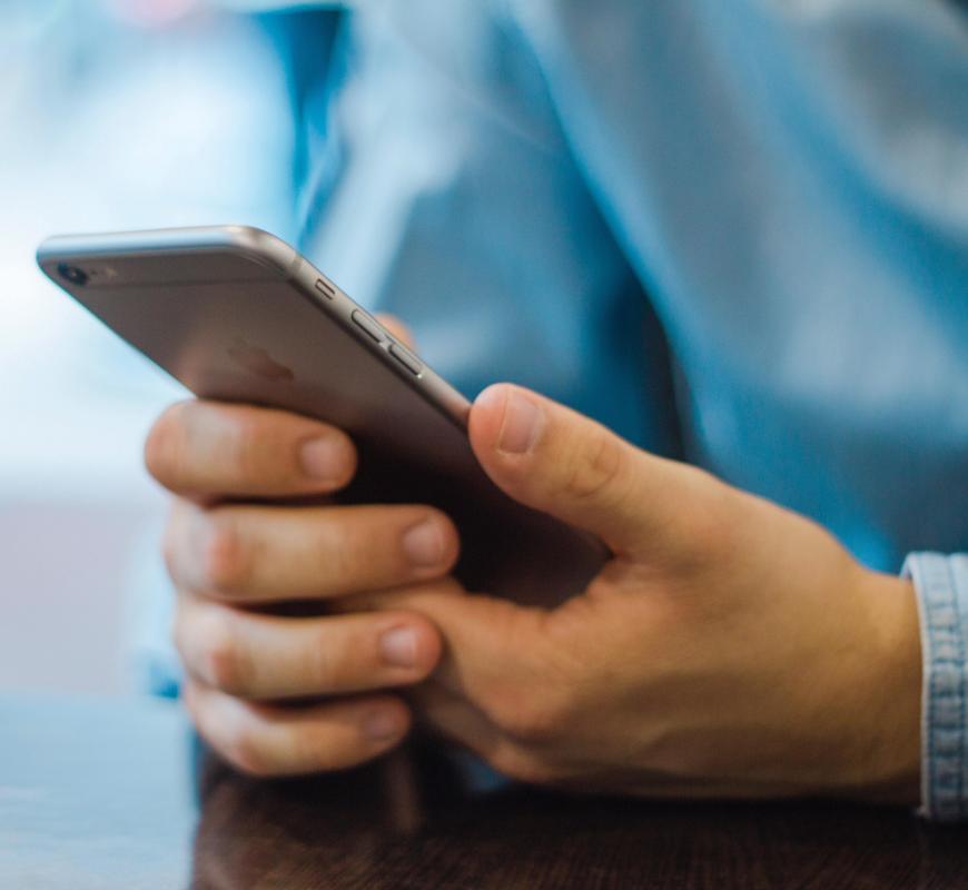 Primer plano de una persona que utiliza un smartphone: estrategias de marketing digital y boletines informativos para captar clientes potenciales.