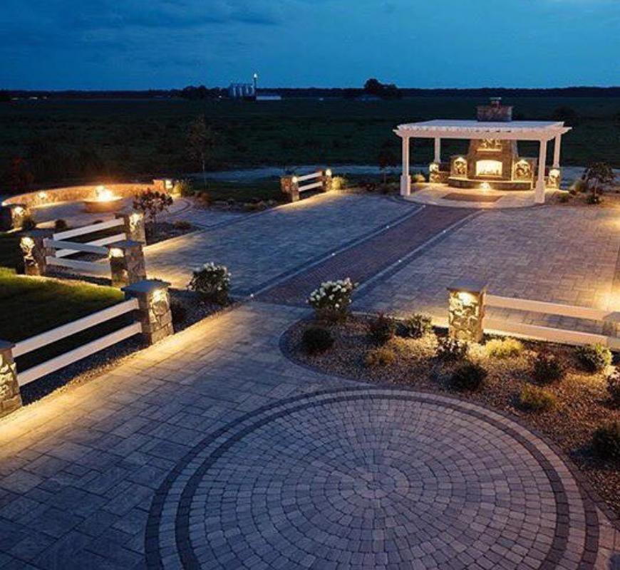 Patio trasero nocturno con iluminación incorporada, zonas para sentarse y una estructura cubierta, que pone de relieve las tendencias actuales de la vida al aire libre.